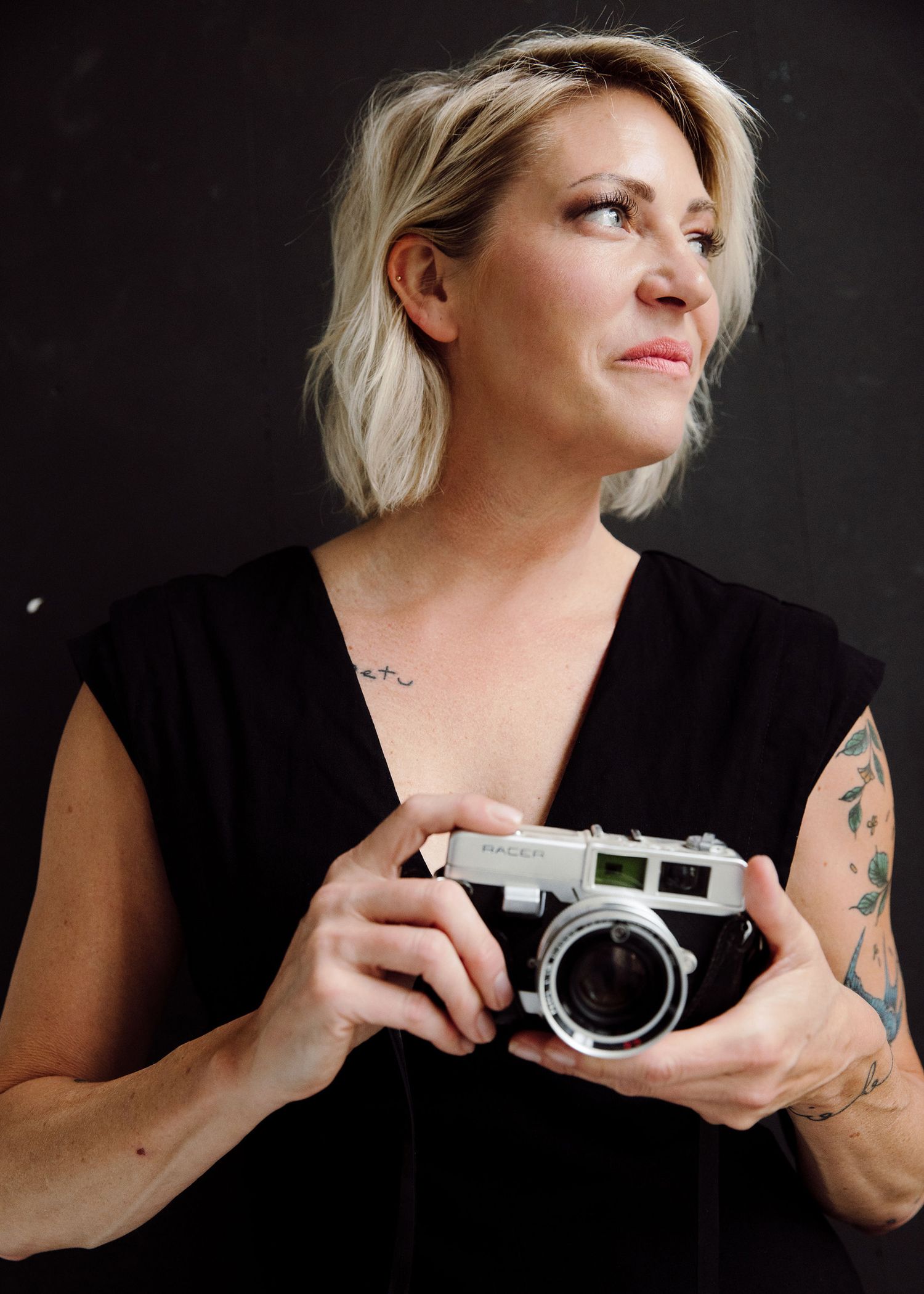 Portrait series featuring photographer holding vintage camera in black outfit against dark background.
