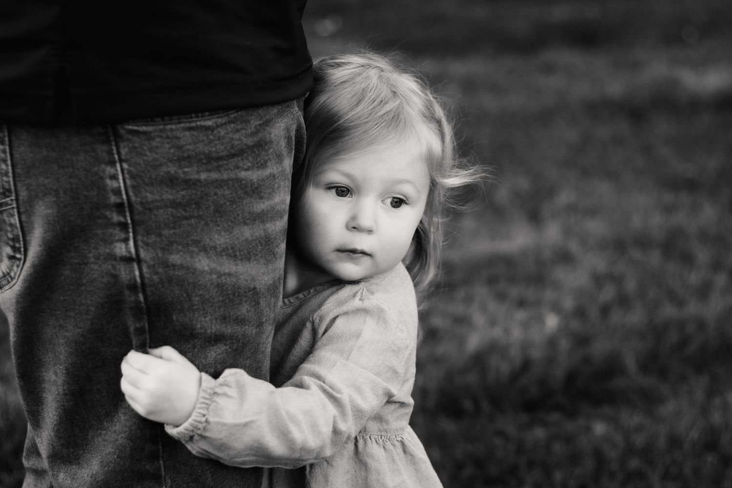 Photographer capturing a candid moment of child grabbing dad's leg during a family session, Metro Detroit family photographer