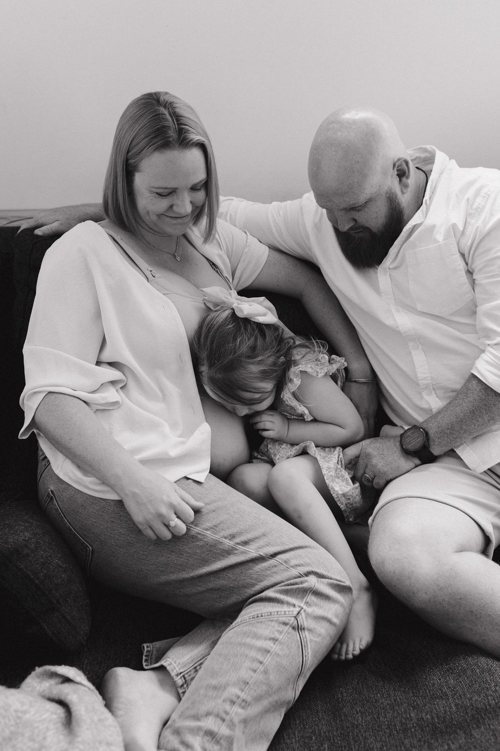 A tender black and white family moment captured on a couch as parents comfort their small child.