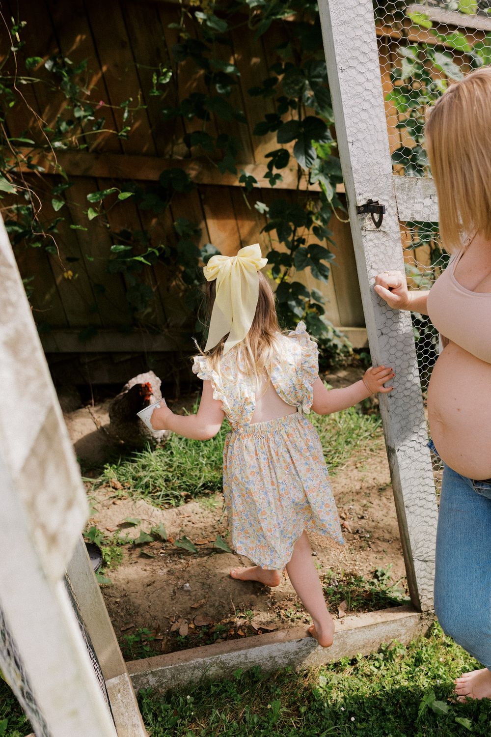 Multiple shots of a young child in a light-colored dress playing near a white wall outdoors.