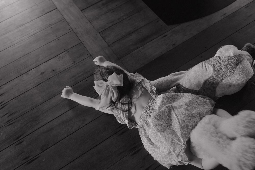 A sequence of black and white photographs showing a dog lying down and rolling over on a wooden floor.