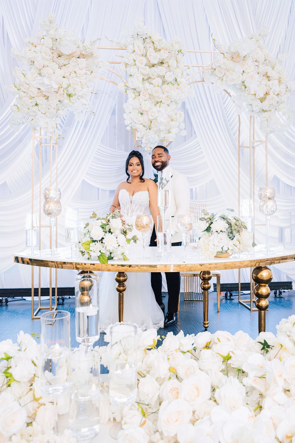 Elegant wedding reception decor features a rustic wooden table adorned with white floral arrangements and crystal candelabras.
