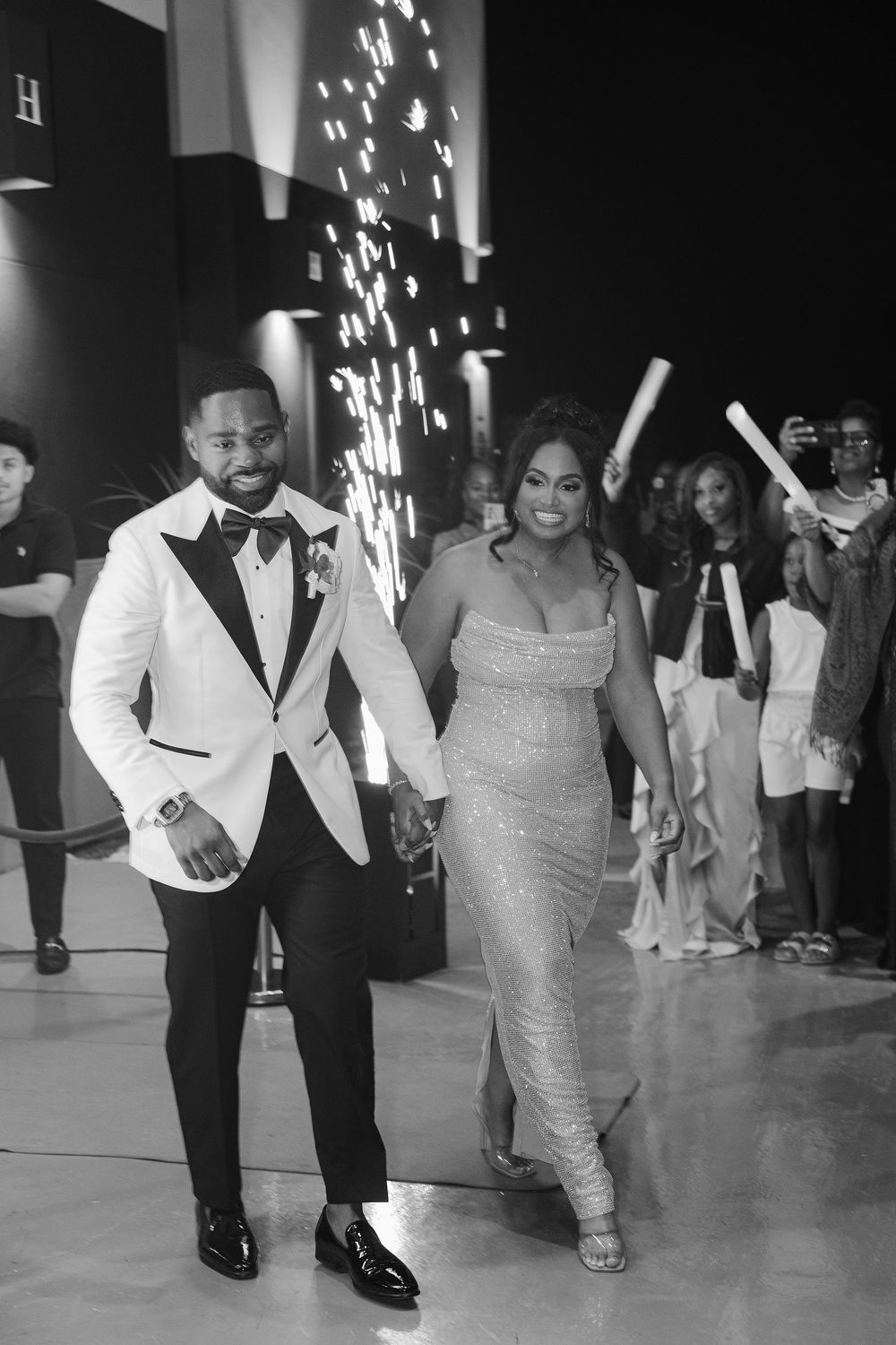 A couple dances together at a wedding reception, with the woman in a sparkly dress and the man in formal attire.