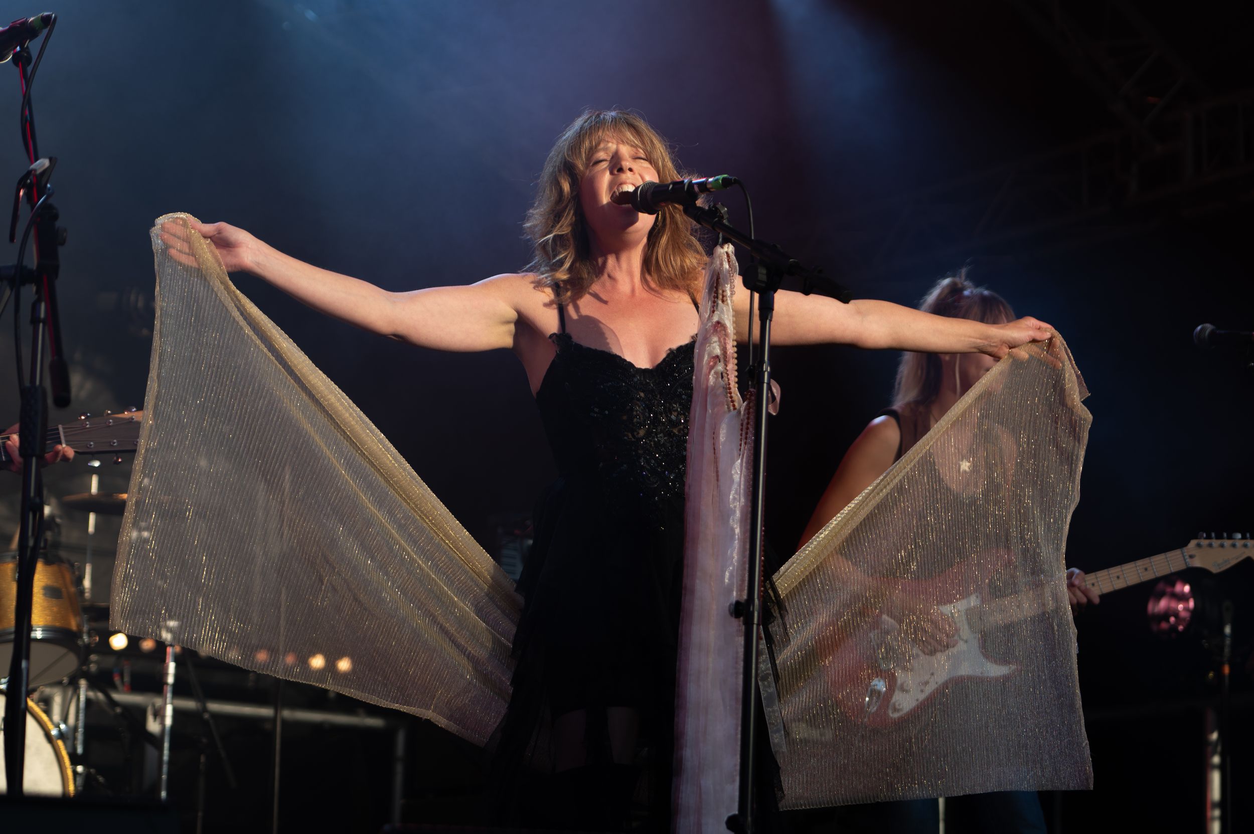 Musicians perform energetically on a dark stage with dramatic lighting and instruments.