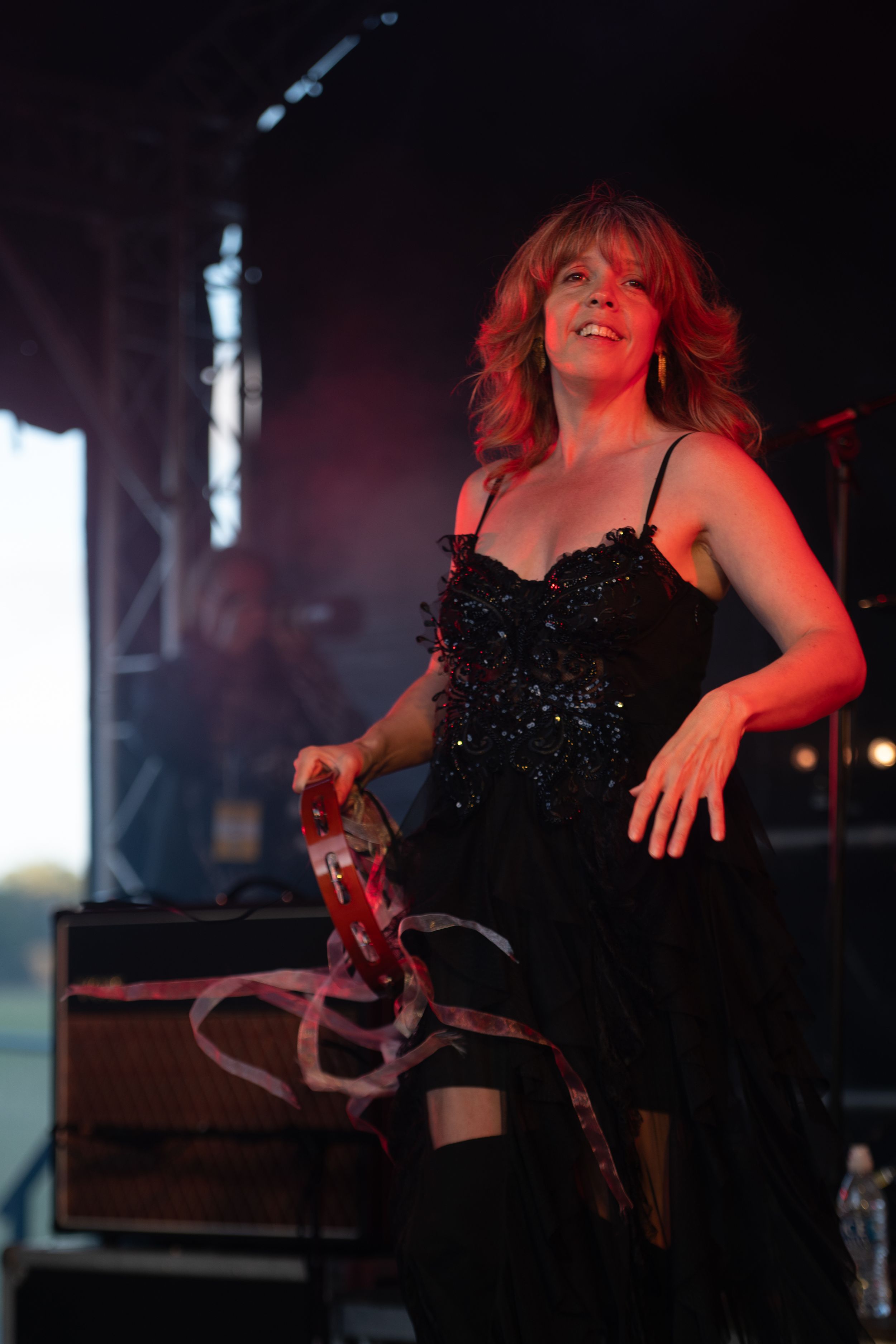 A performer in a sparkly black dress dances energetically on stage during a concert performance.
