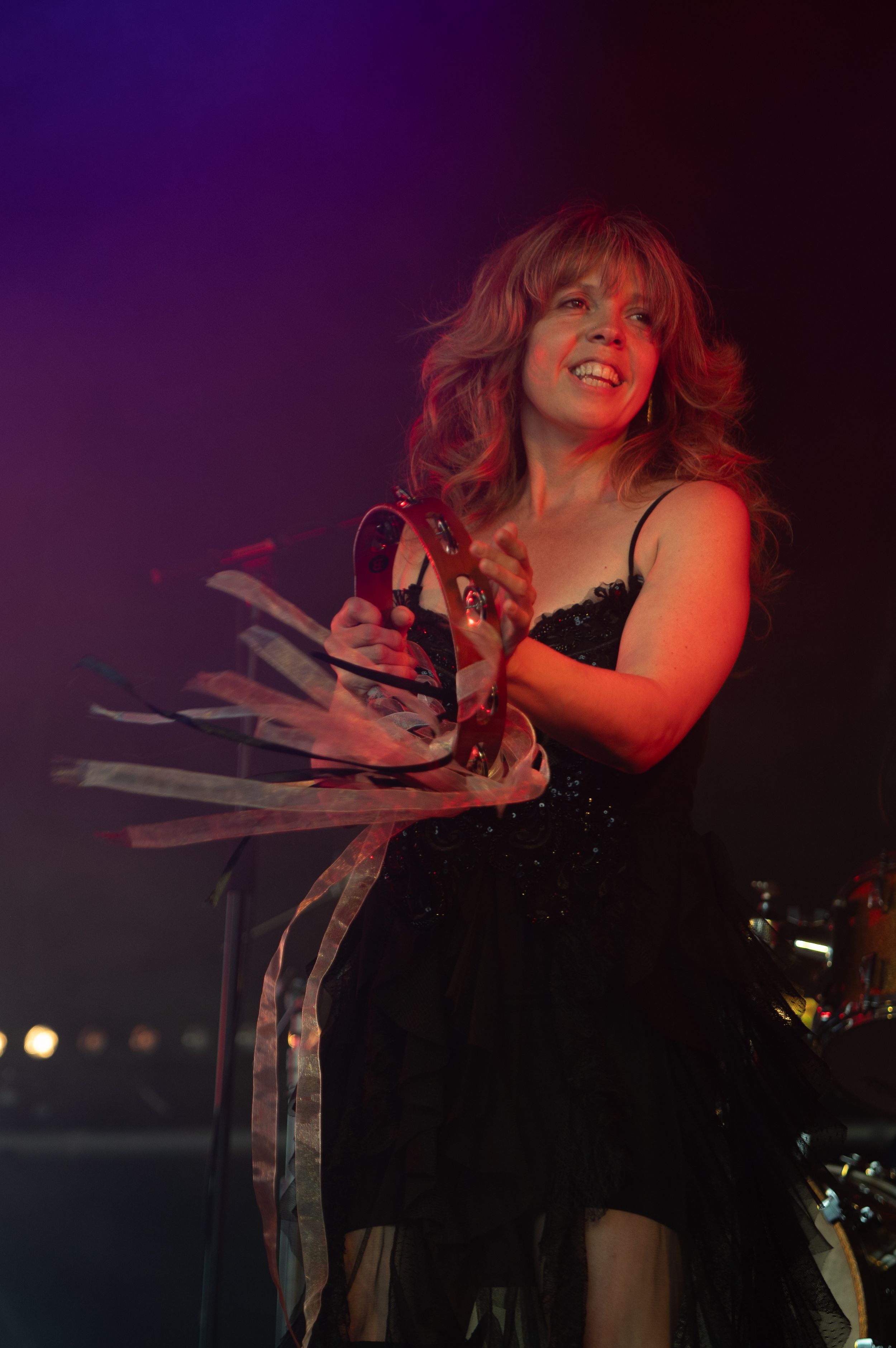 Performer in dramatic red lighting on stage during an energetic musical performance.