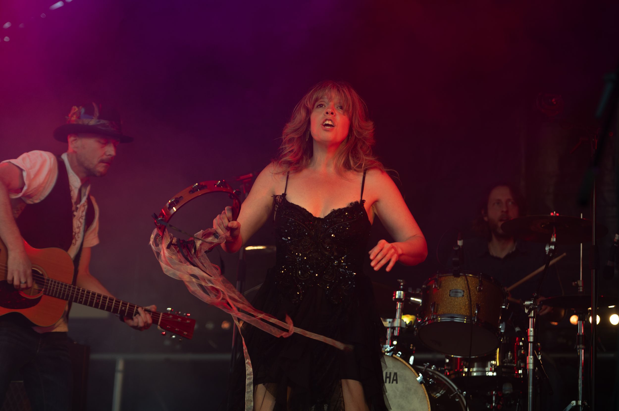 Musicians perform on stage in a dimly lit venue with purple lighting creating a moody atmosphere.