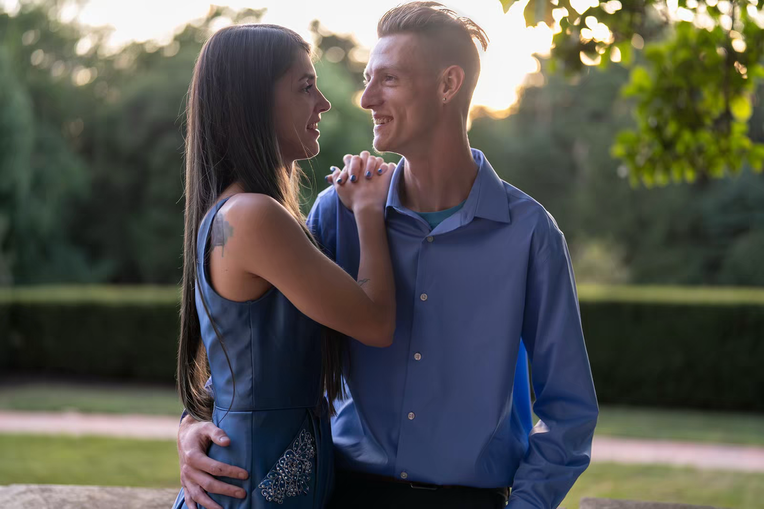 A couple shares a laugh together during an outdoor photo session at sunset.