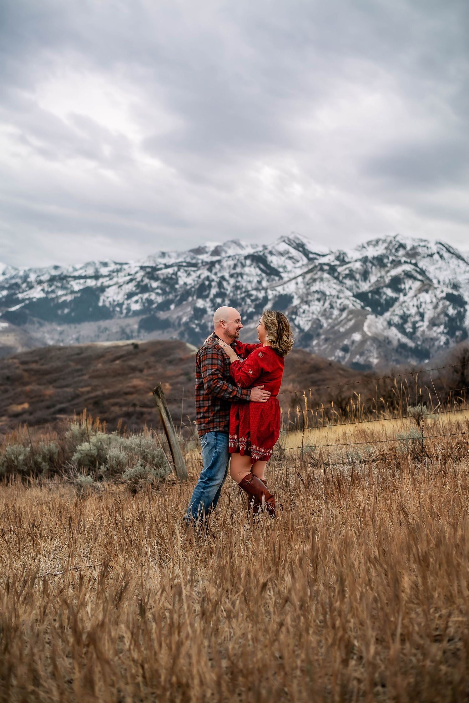Couple in a red dress with snow topped mountains and a field dancing