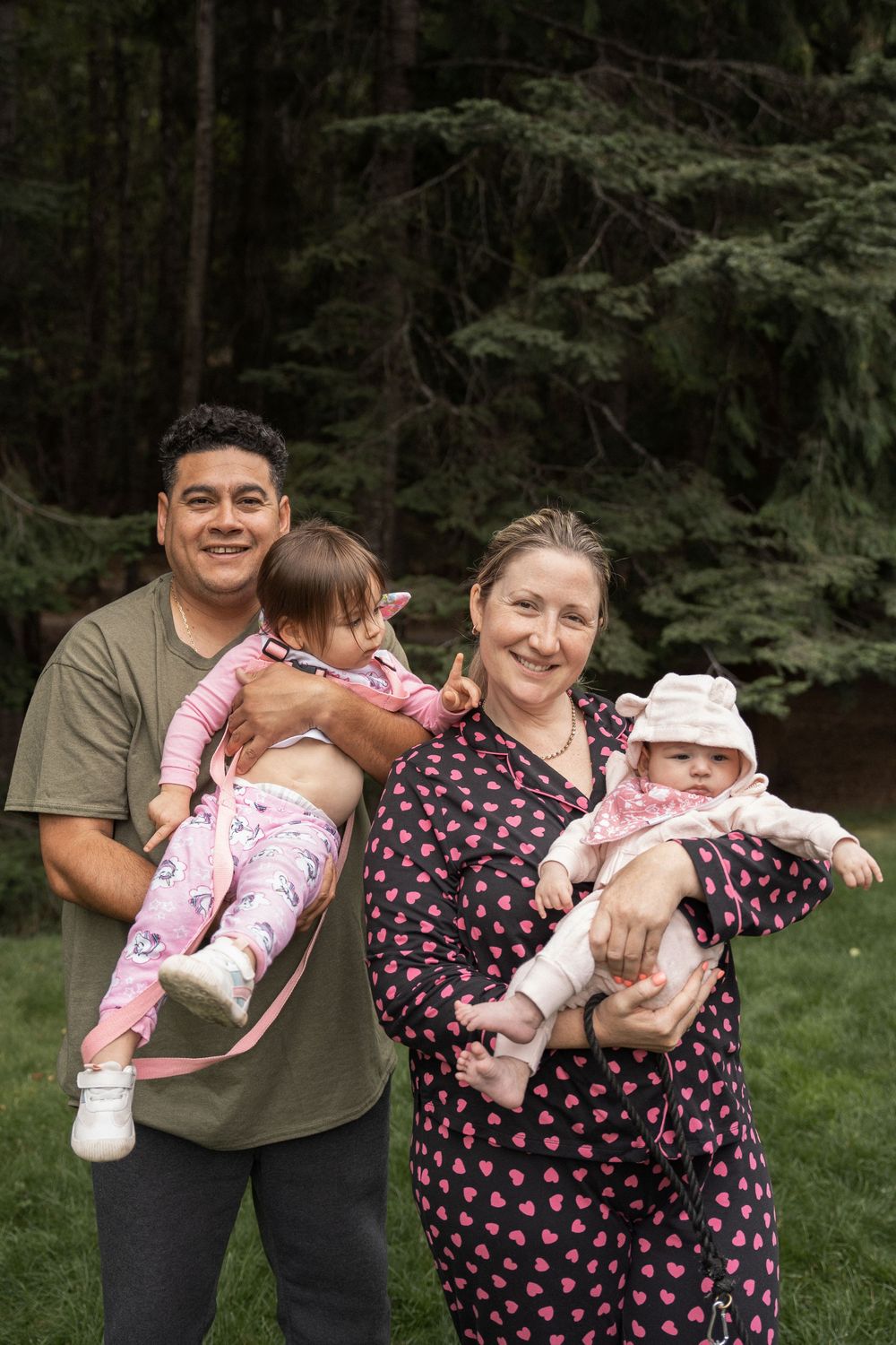 A playful family photoshoot sequence outdoors showing parents and baby in matching outfits against a wooded backdrop.