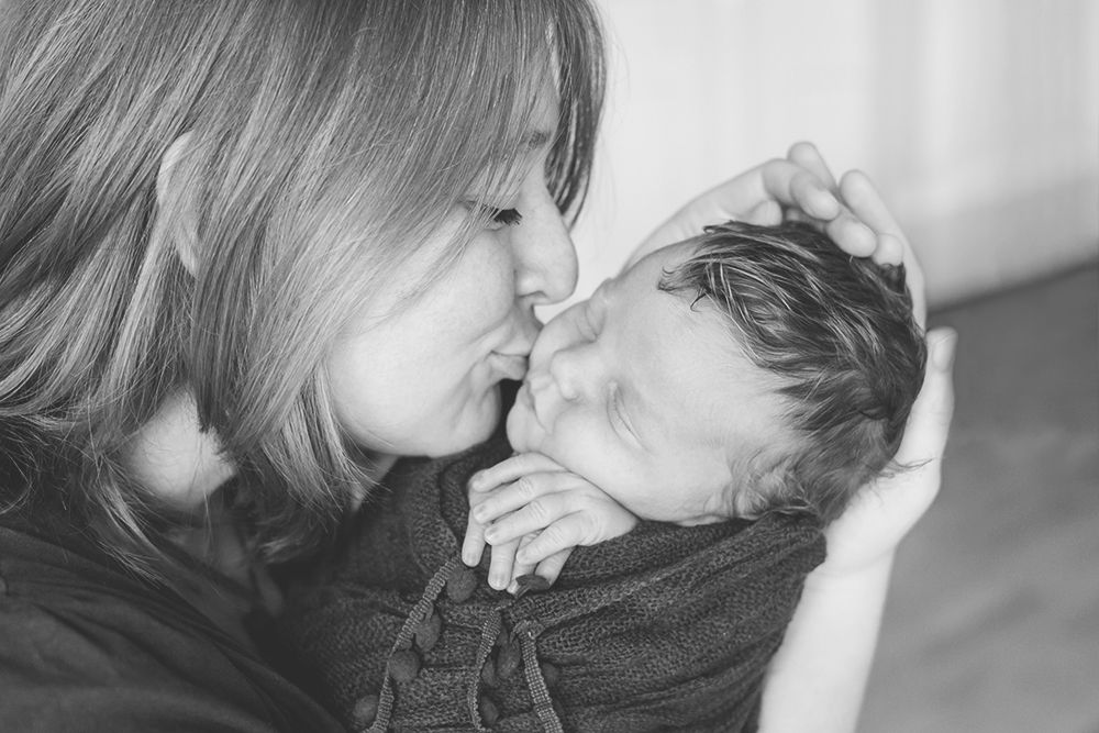 Neugeborenenfotografie, Mutter küsst Baby auf die Wange