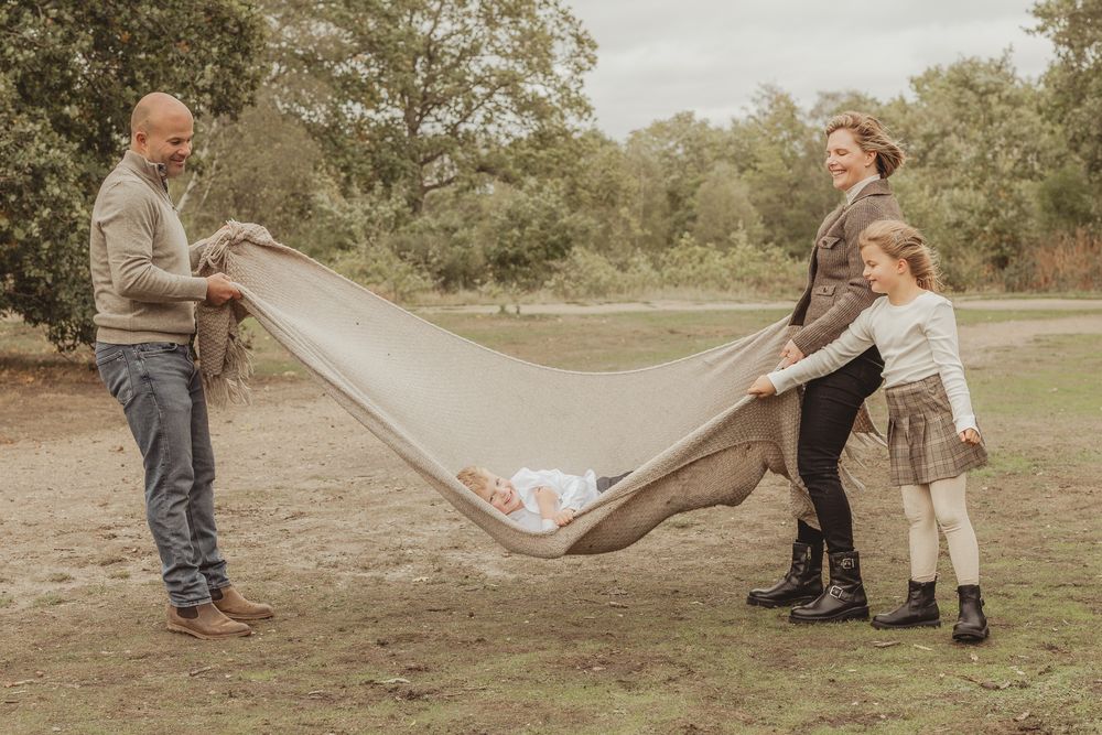 A series of playful outdoor moments captured in a field with people using a blanket to create movement and fun.