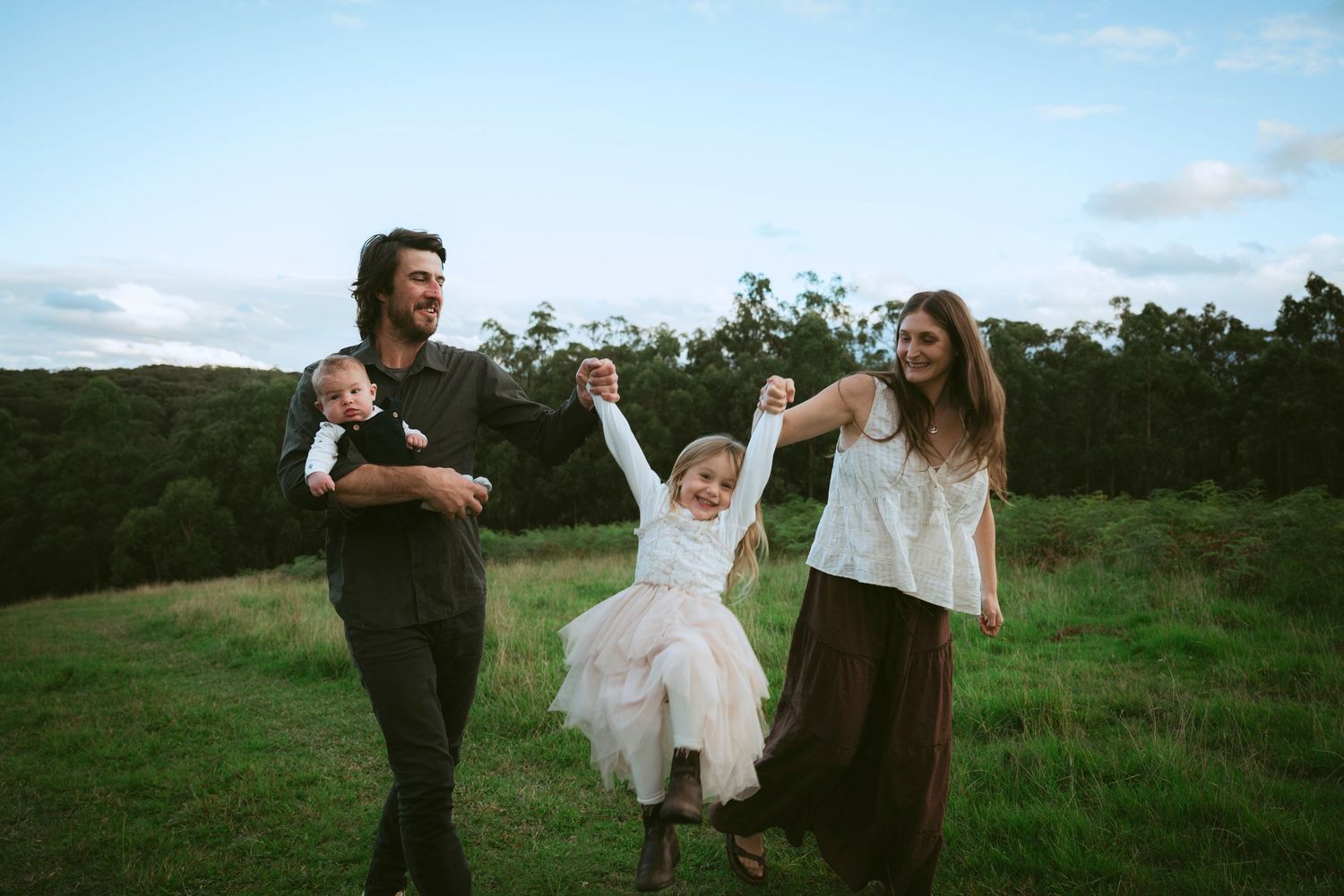 Person in pink dress sitting on large rock in wooded forest setting.
