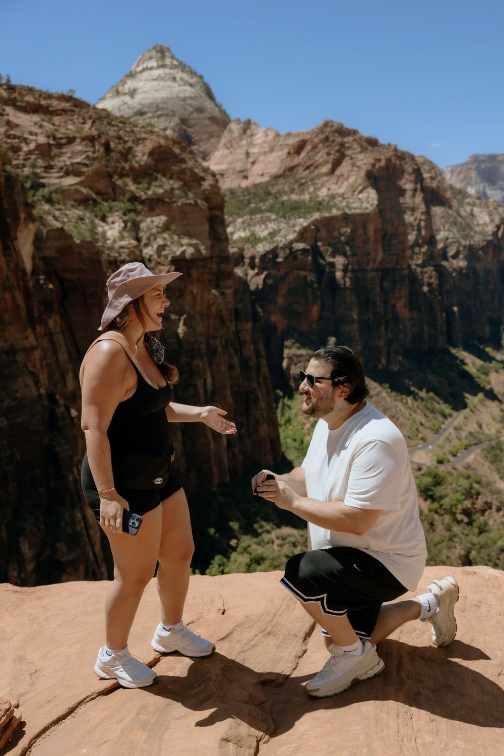 A proposal moment captured against the dramatic backdrop of red rock cliffs at Zion National Park.