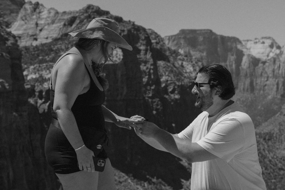 A couple shares a romantic moment at Zion National Park with majestic red rock cliffs in the background.
