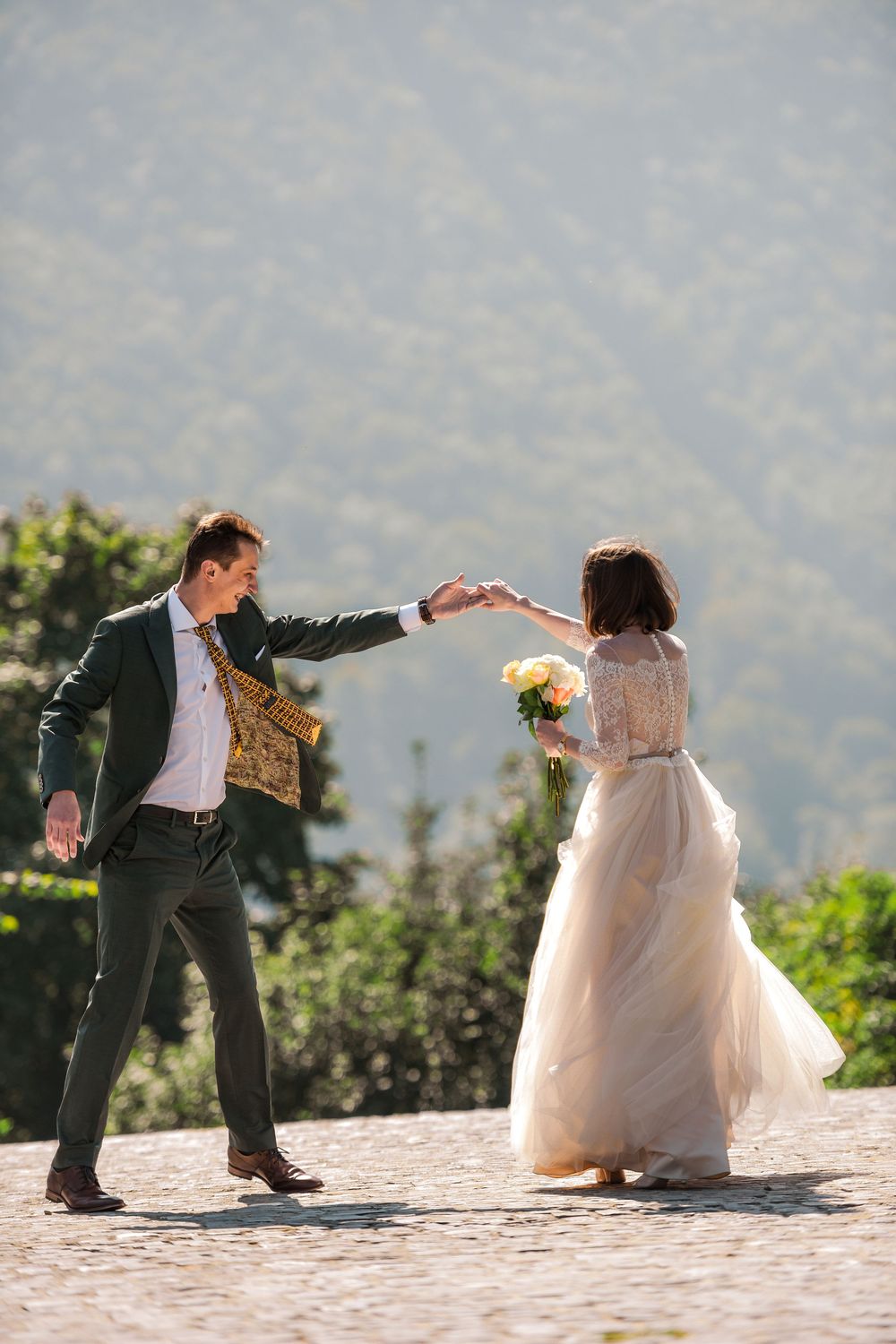 Creative wedding photo sequence shows couple playfully posing in dance moves on a scenic mountain overlook.