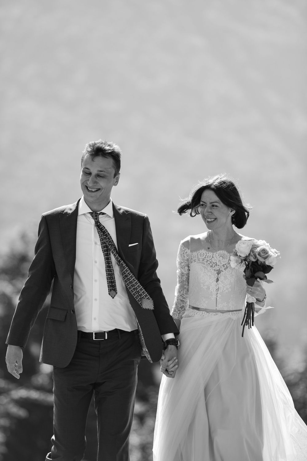 A joyful wedding couple walking and laughing together in black and white photography.