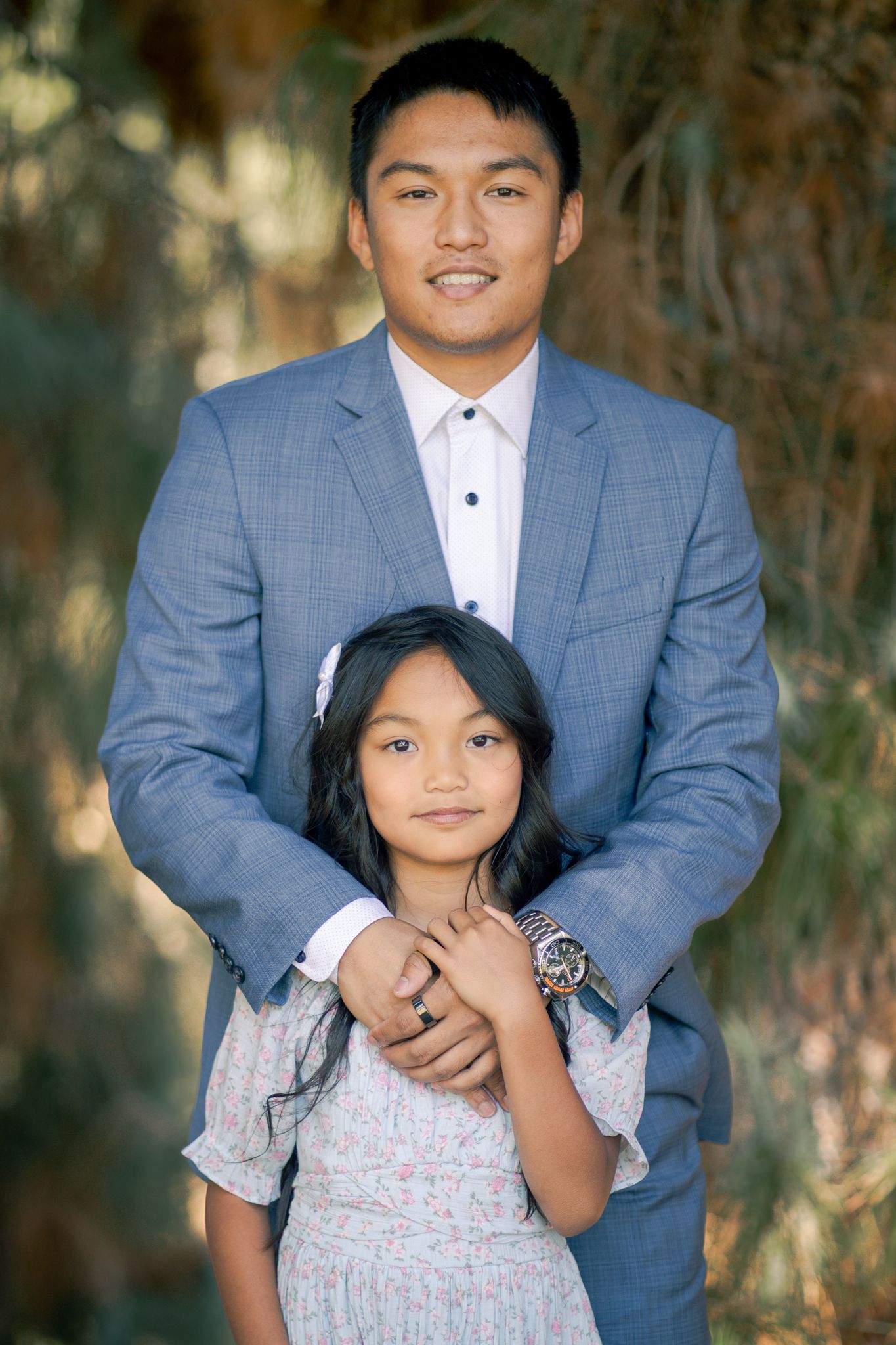 A couple in coordinating blue and white outfits pose together in an outdoor portrait session.