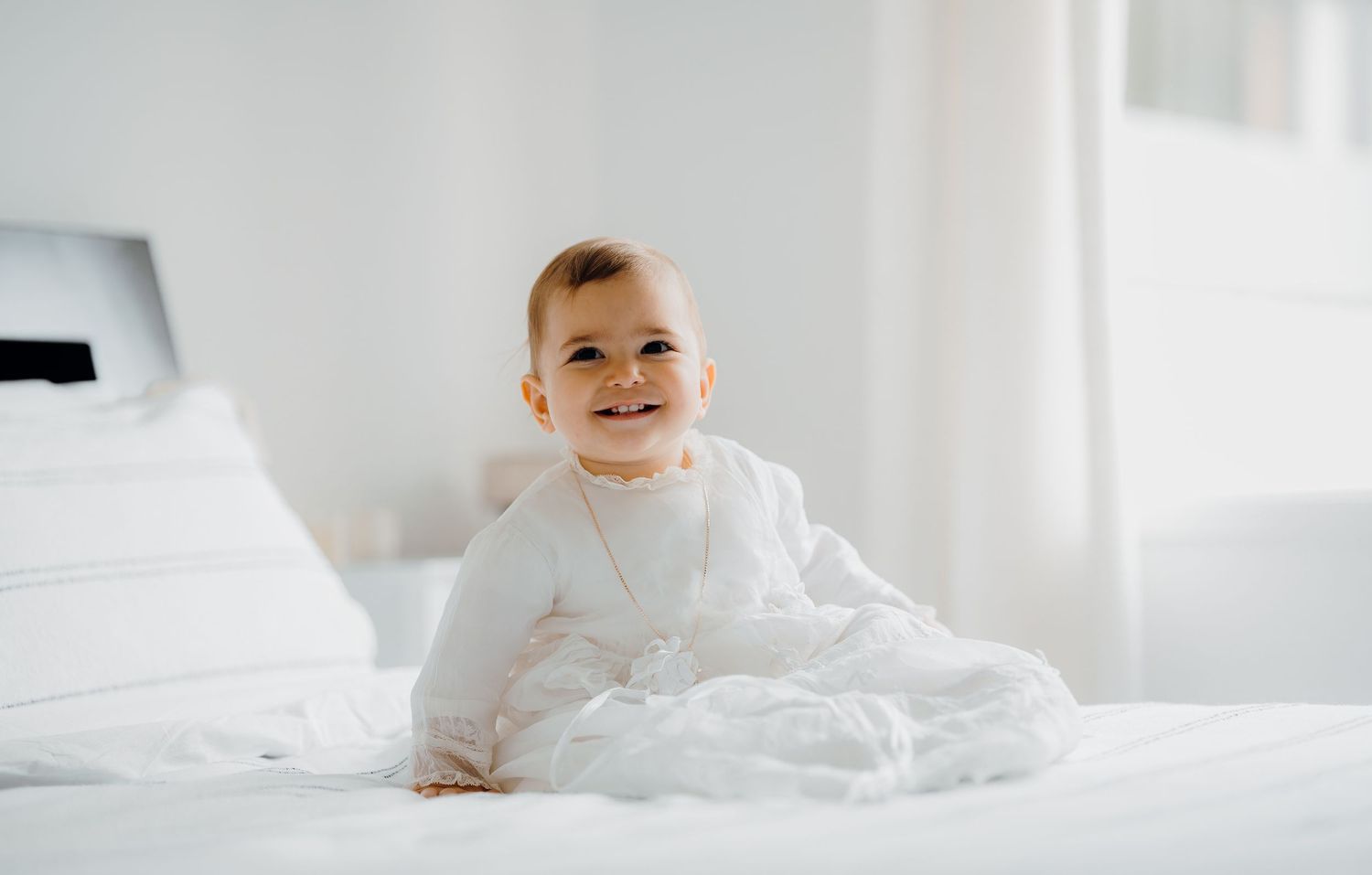 A series of four images showing a small child playing and smiling in white bedding and blankets.