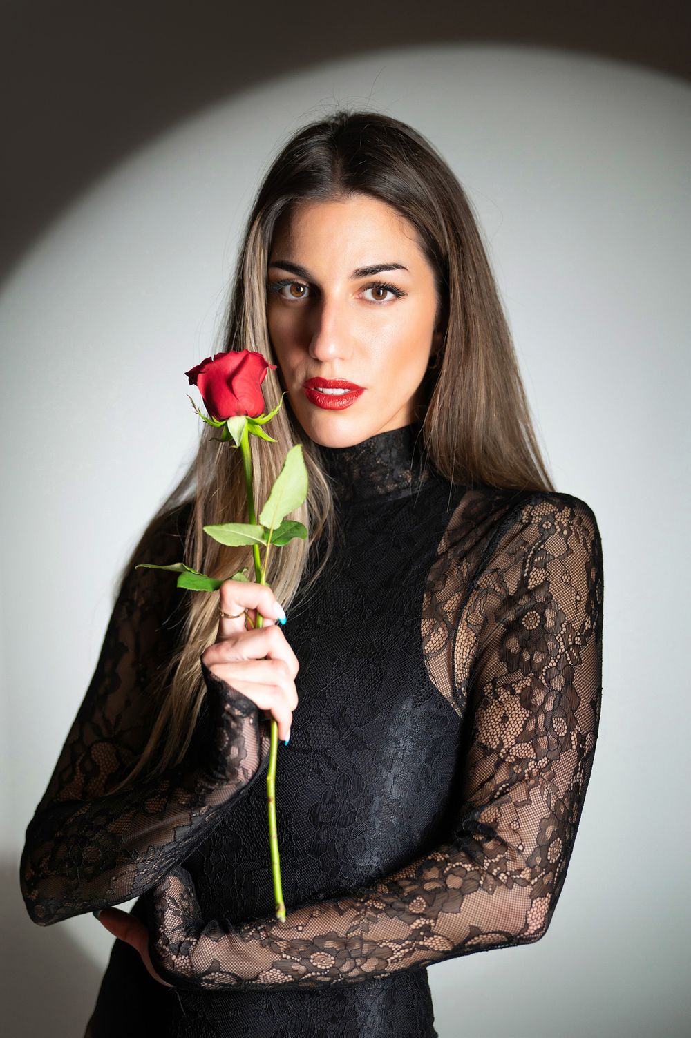 A series of artistic portraits featuring someone in a black lace top holding a red rose against a light background.