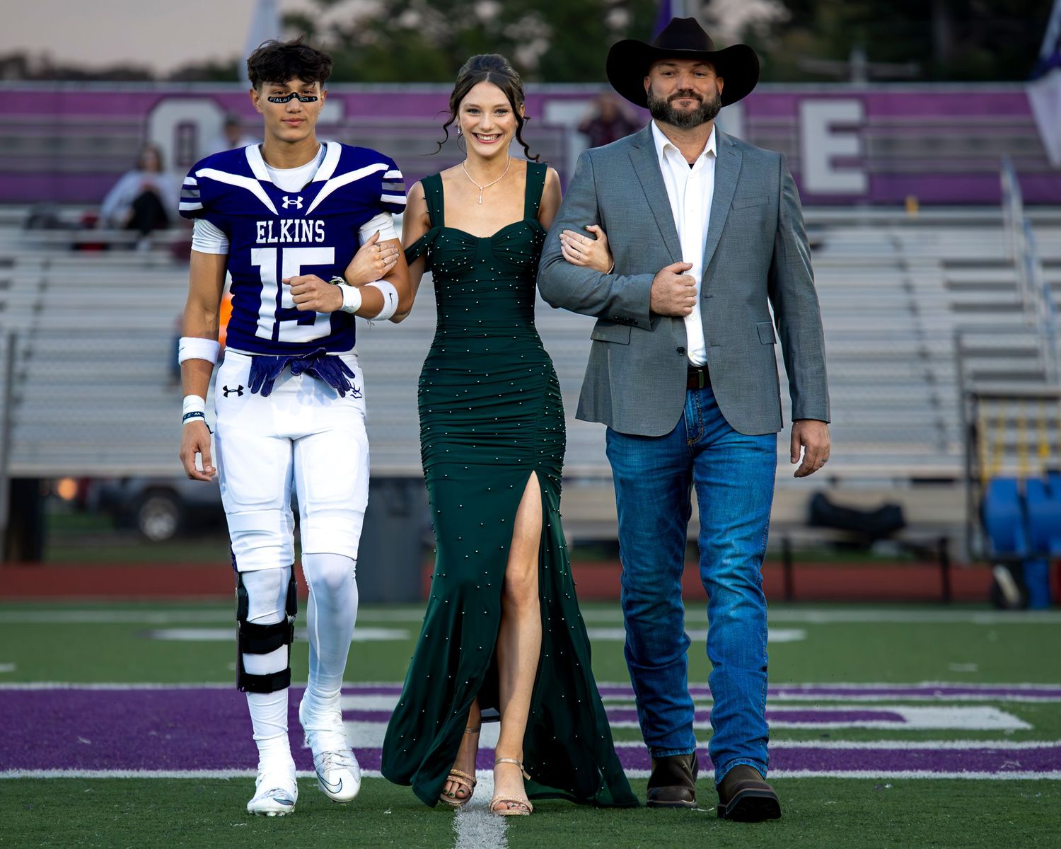 Football players and guests walk across a sports field during a special ceremony or event.