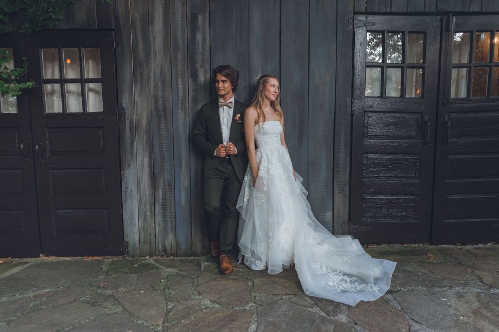A wedding couple poses in front of rustic black wooden doors for a series of romantic photos.