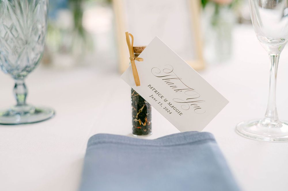 Elegant wedding place settings with blue and white decor, crystal glasses, and delicate name cards on a light tablecloth.