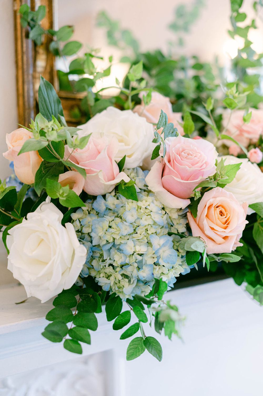 Elegant floral arrangement with pink roses and blue hydrangeas on a white surface.
