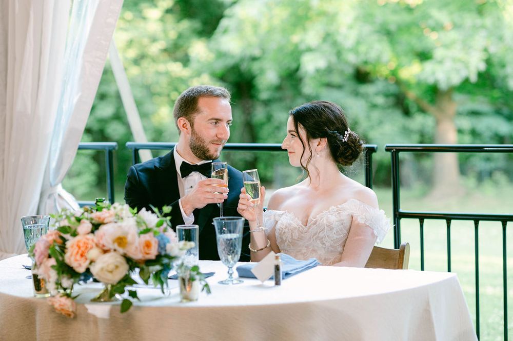 Elegant wedding reception setup under a white tent with natural lighting.