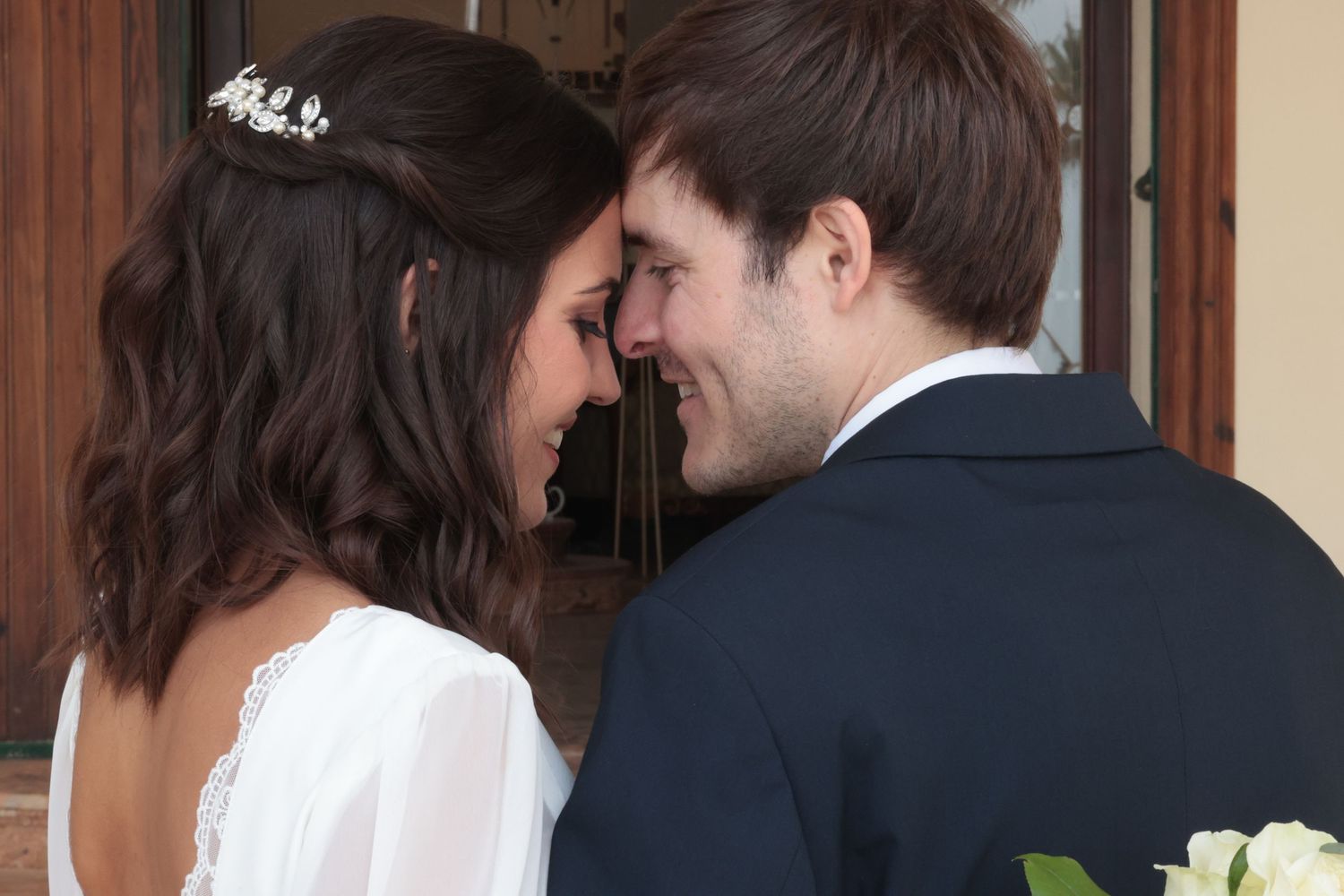Pareja de novios románticos abrazándose tiernamente, compartiendo un momento de amor con las frentes juntas y los ojos cerrados, celebrando