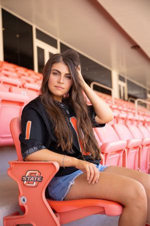 A series of four photos showing someone posing in a black shirt and denim on orange stadium seats.
