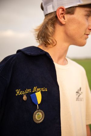 Close-up sequence showing embroidered FFA logo and medal details on a navy blue jacket.