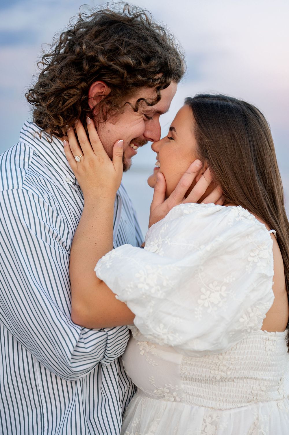 An intimate close-up of a couple sharing romantic moments on a beach.