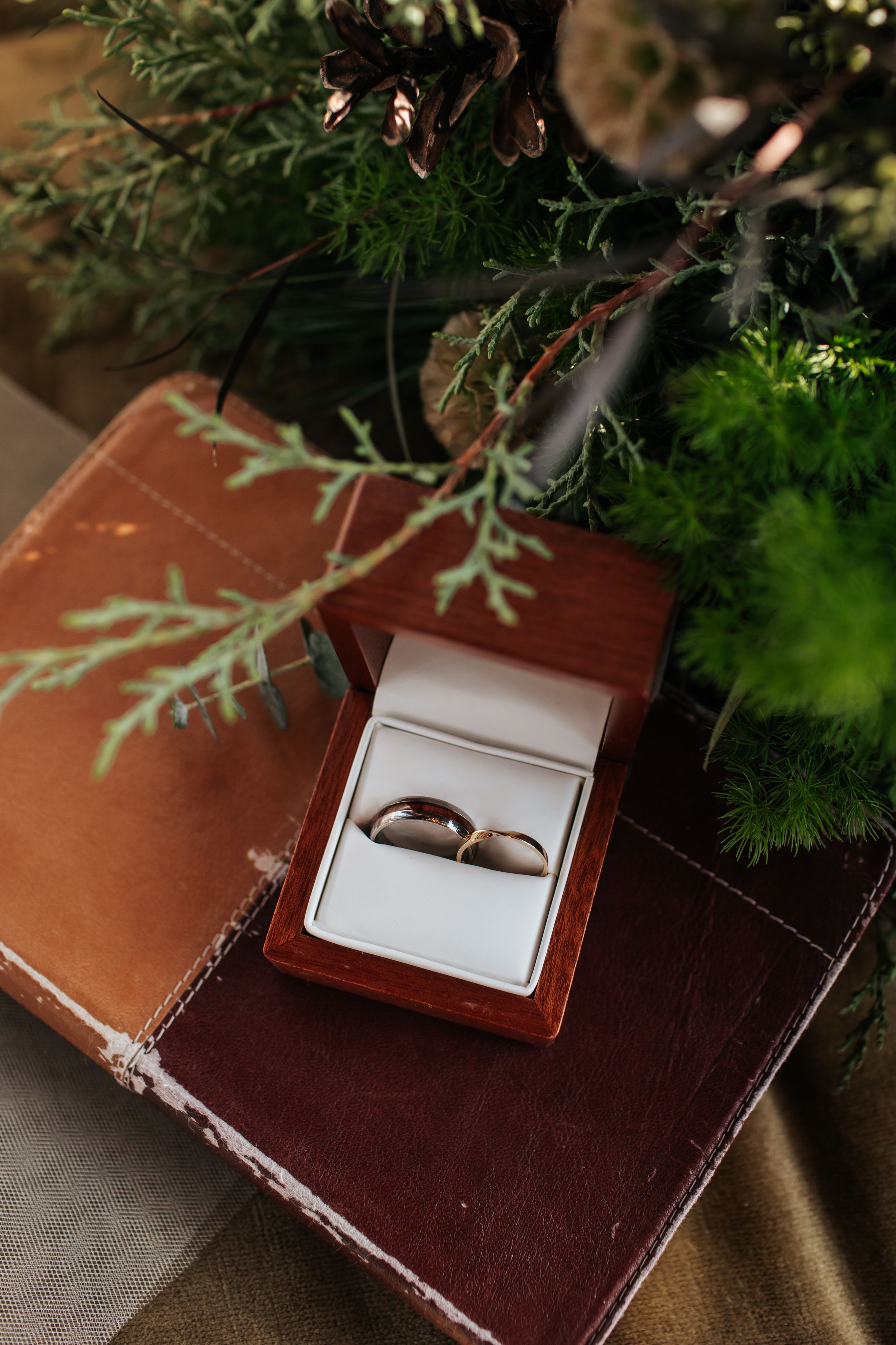 Brown leather wedding album or photo book displayed with delicate greenery and natural lighting.