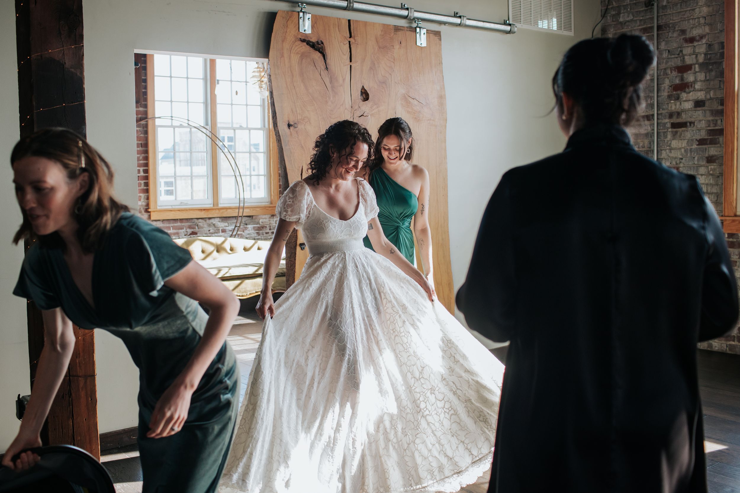 A wedding party gathers in a rustic brick-walled room during preparations for the ceremony.