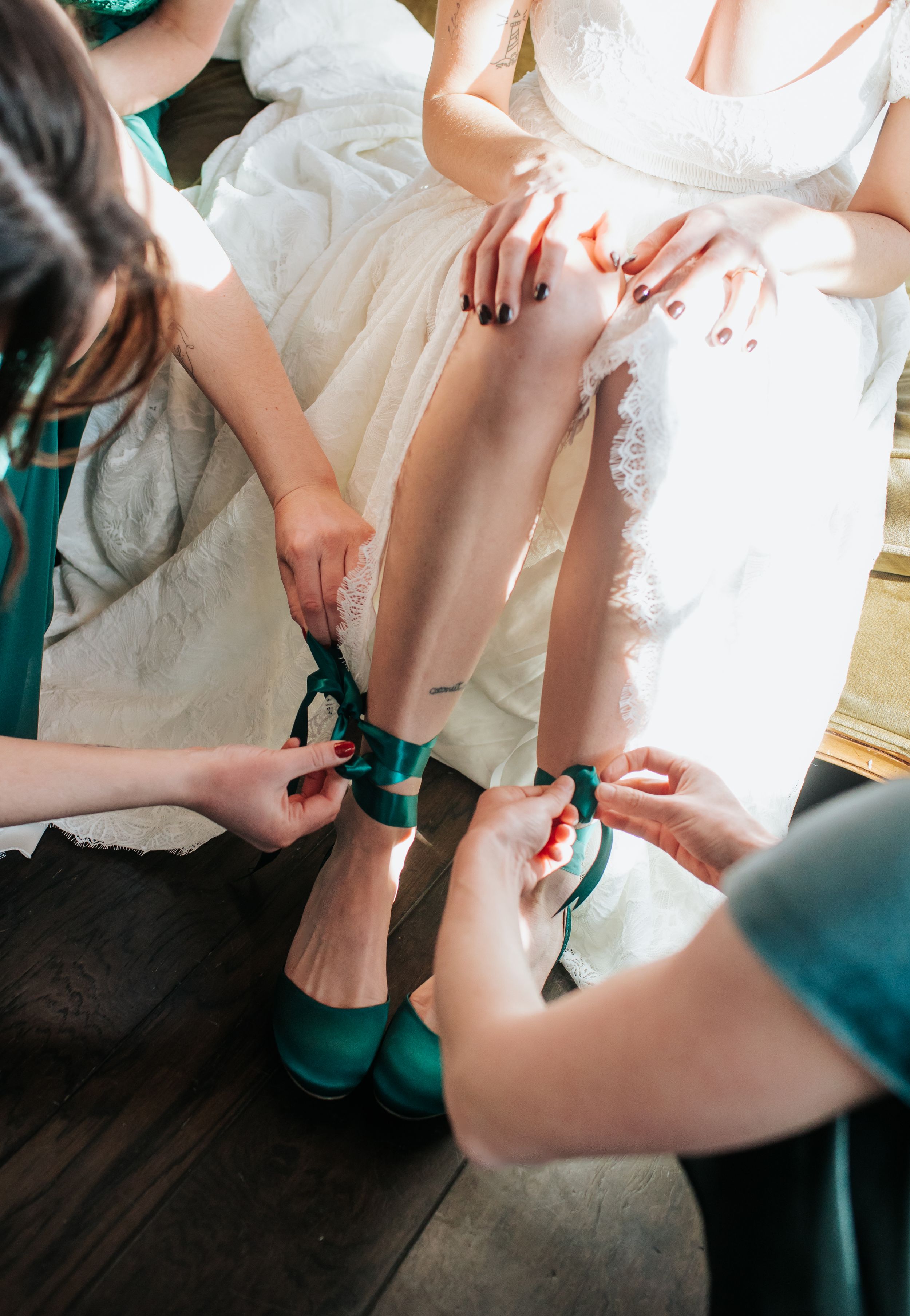A close-up shot of emerald green heels being put on during wedding preparation.