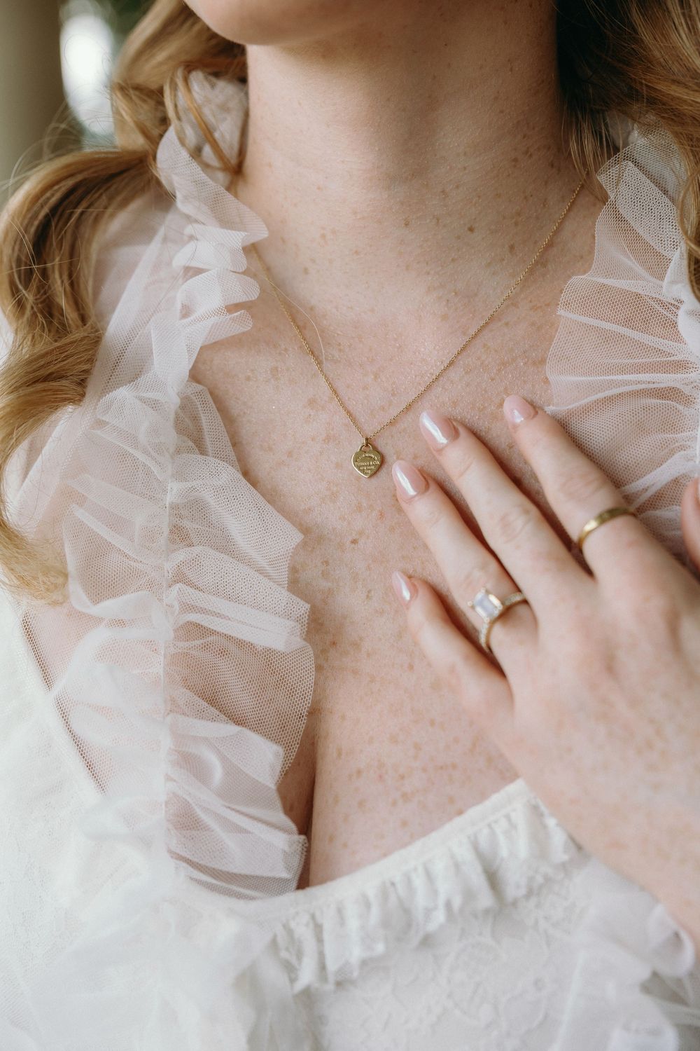 Close-up detail shots of delicate white ruffled fabric and jewelry against pale skin in soft natural light at an Atlanta wedding venue