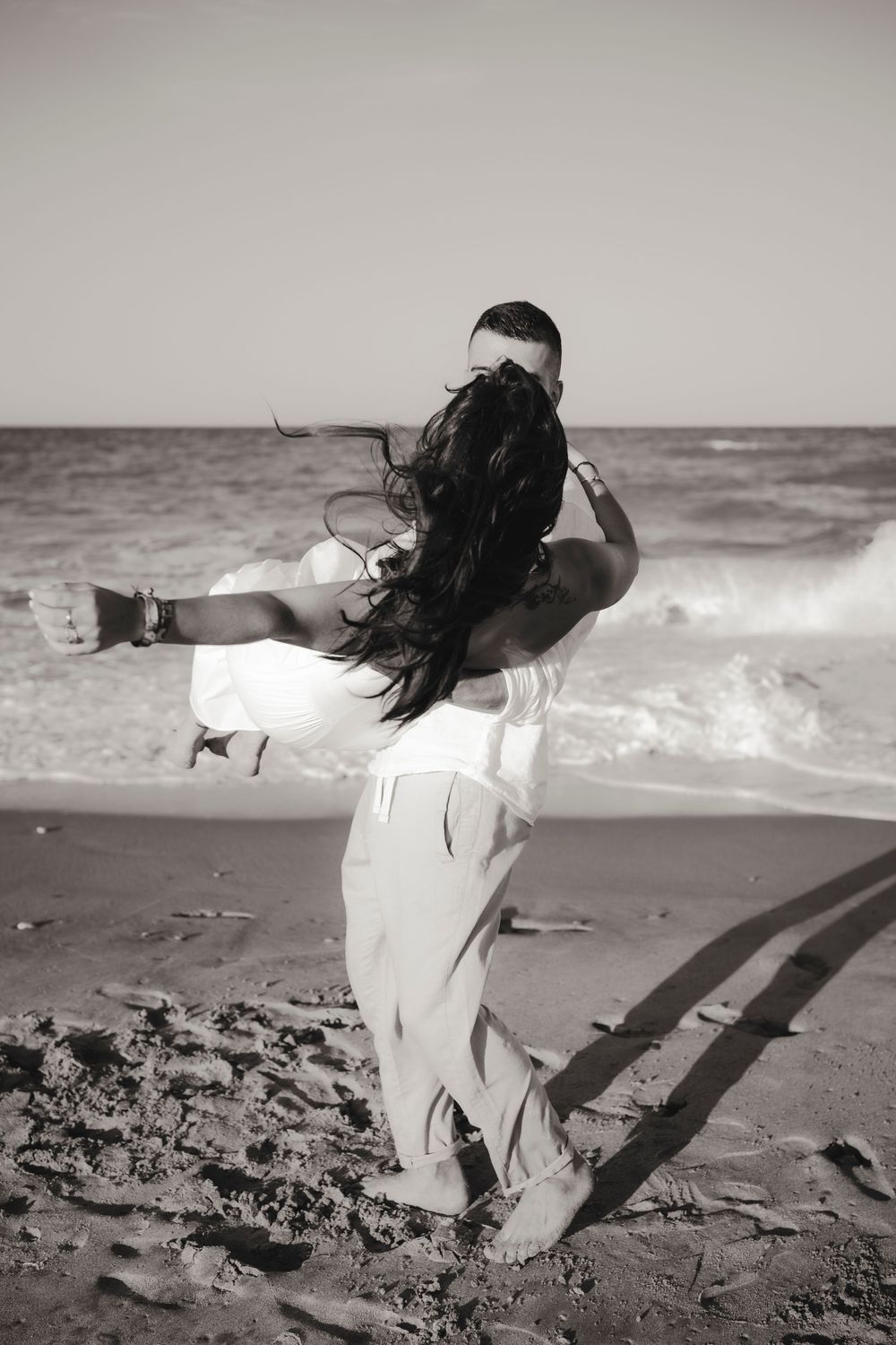 Spontaneous laugh and emotional embrace between a foreign couple during a beach shoot.