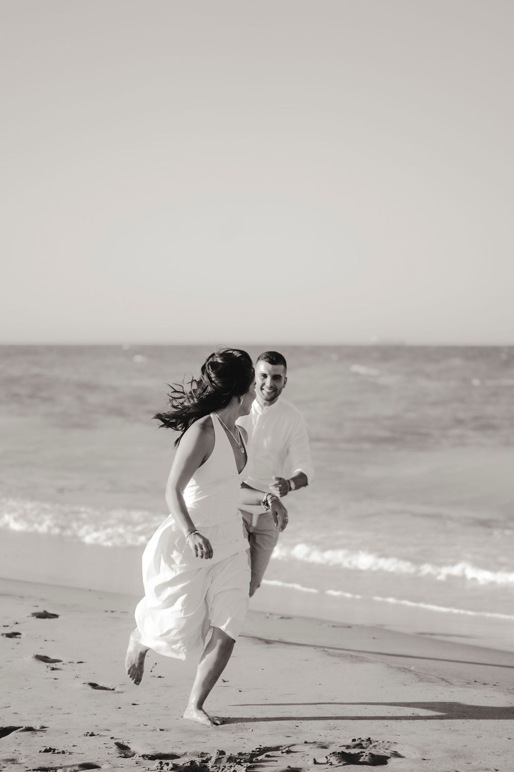 Fine art couple portrait with soft shadows on the sand during a seaside golden hour.