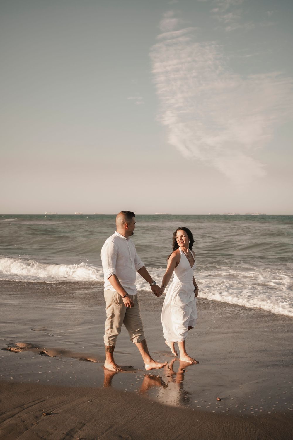 Detail shot of a couple walking barefoot on the wet sand, romantic destination photography.