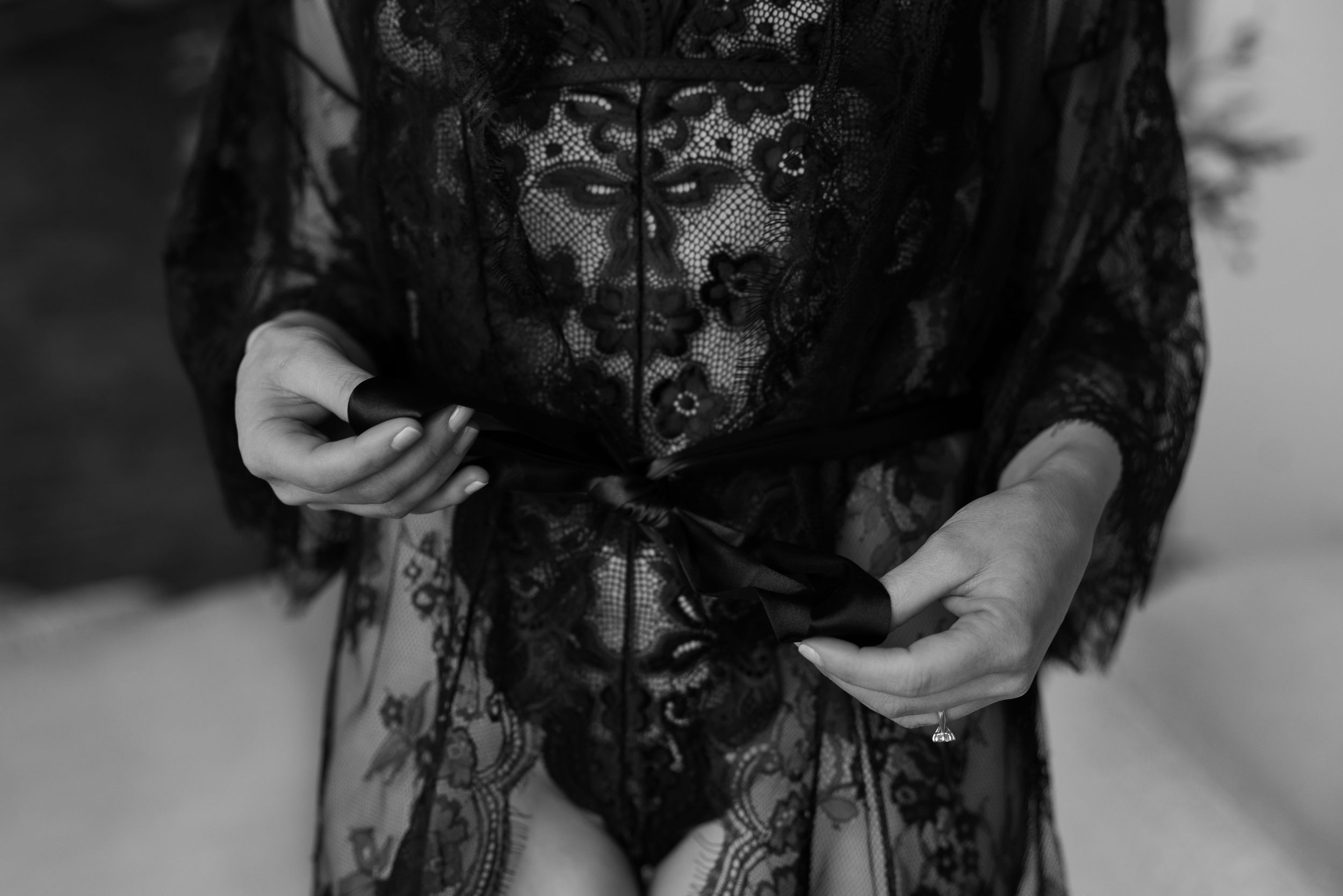 A black lace dress with floral embroidery details is displayed on a mannequin against a white background.