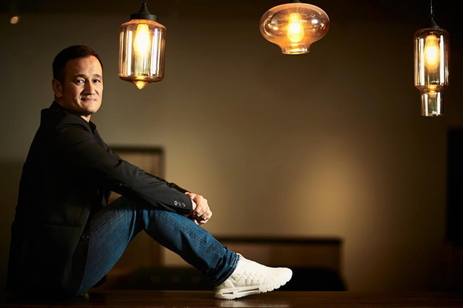 Professional portrait session with warm lighting and casual poses against dark background.
