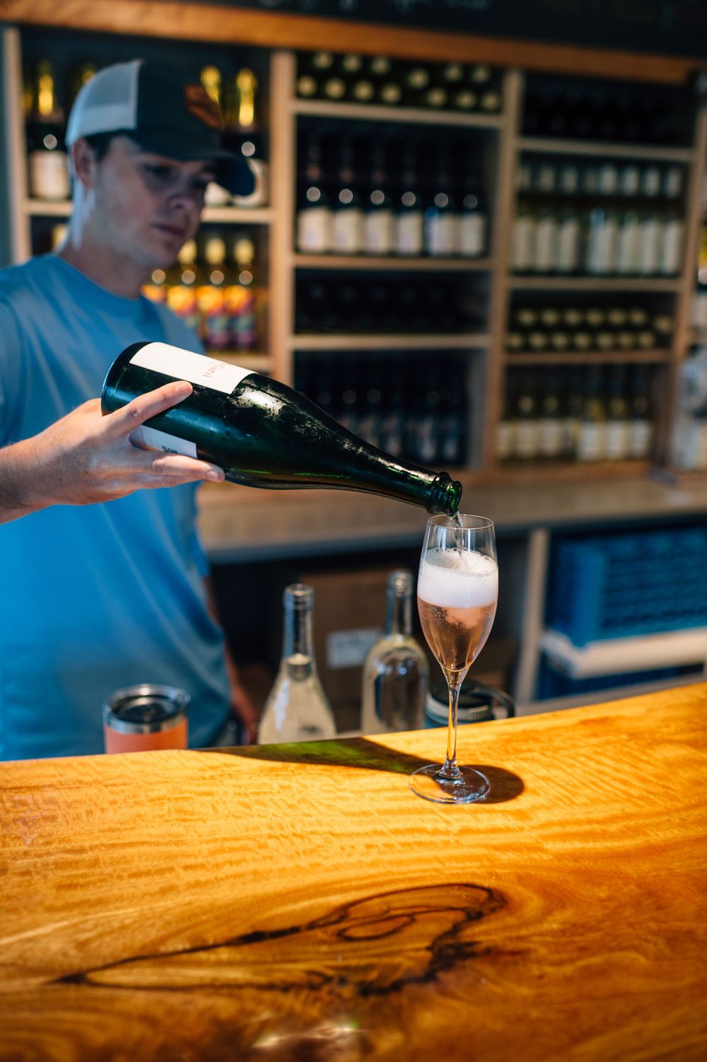 Beer being poured into glasses on a live-edge wooden bar counter.