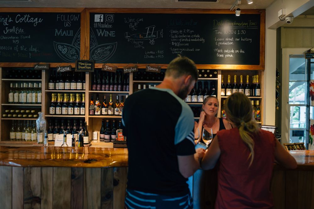 Dark interior of wine bar with chalkboard menu and extensive bottle display.
