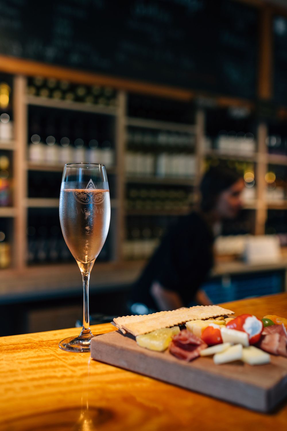 Wine glass and charcuterie board displayed on rustic wooden bar counter.