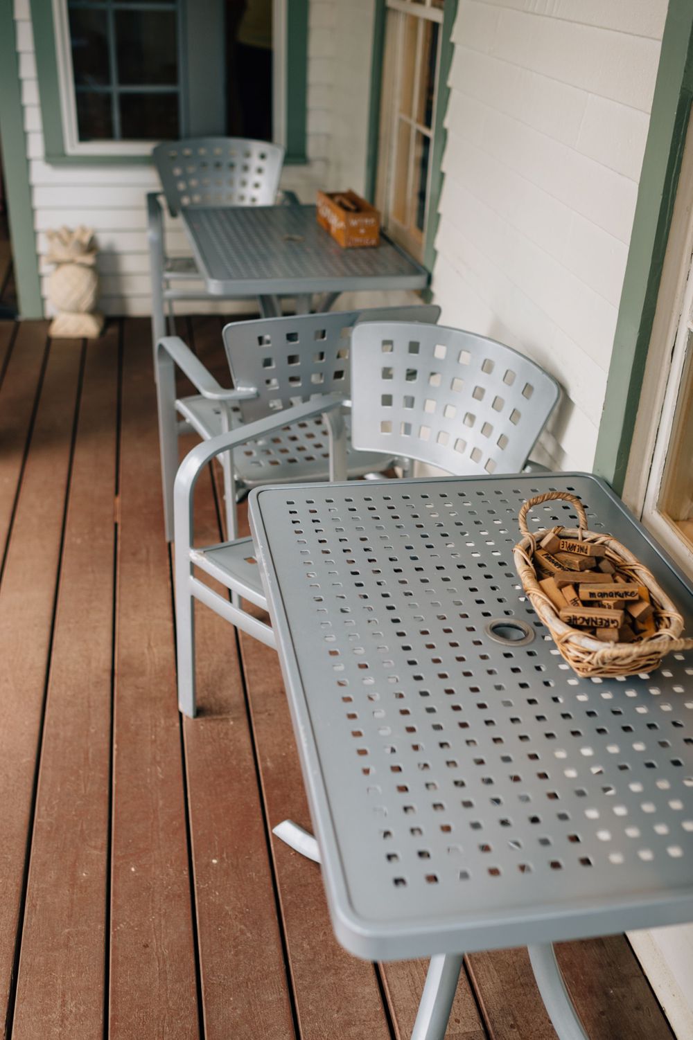 Gray metal chairs arranged on wooden deck with wicker baskets on tables.