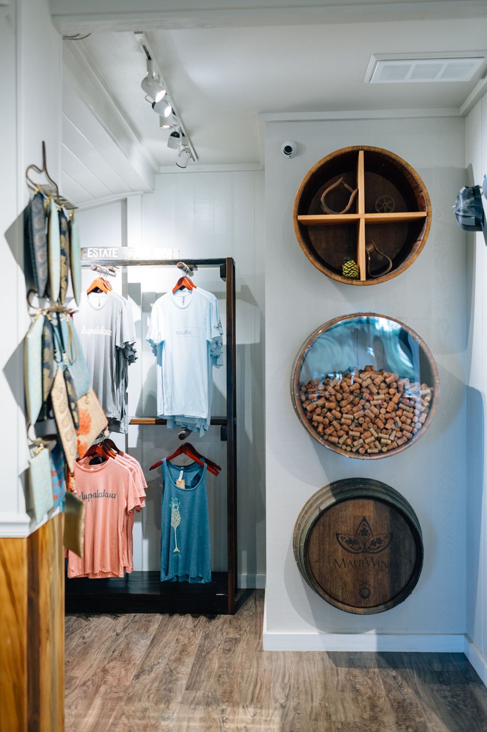 Retail space with wooden barrel displays and clothing racks in a bright white interior.