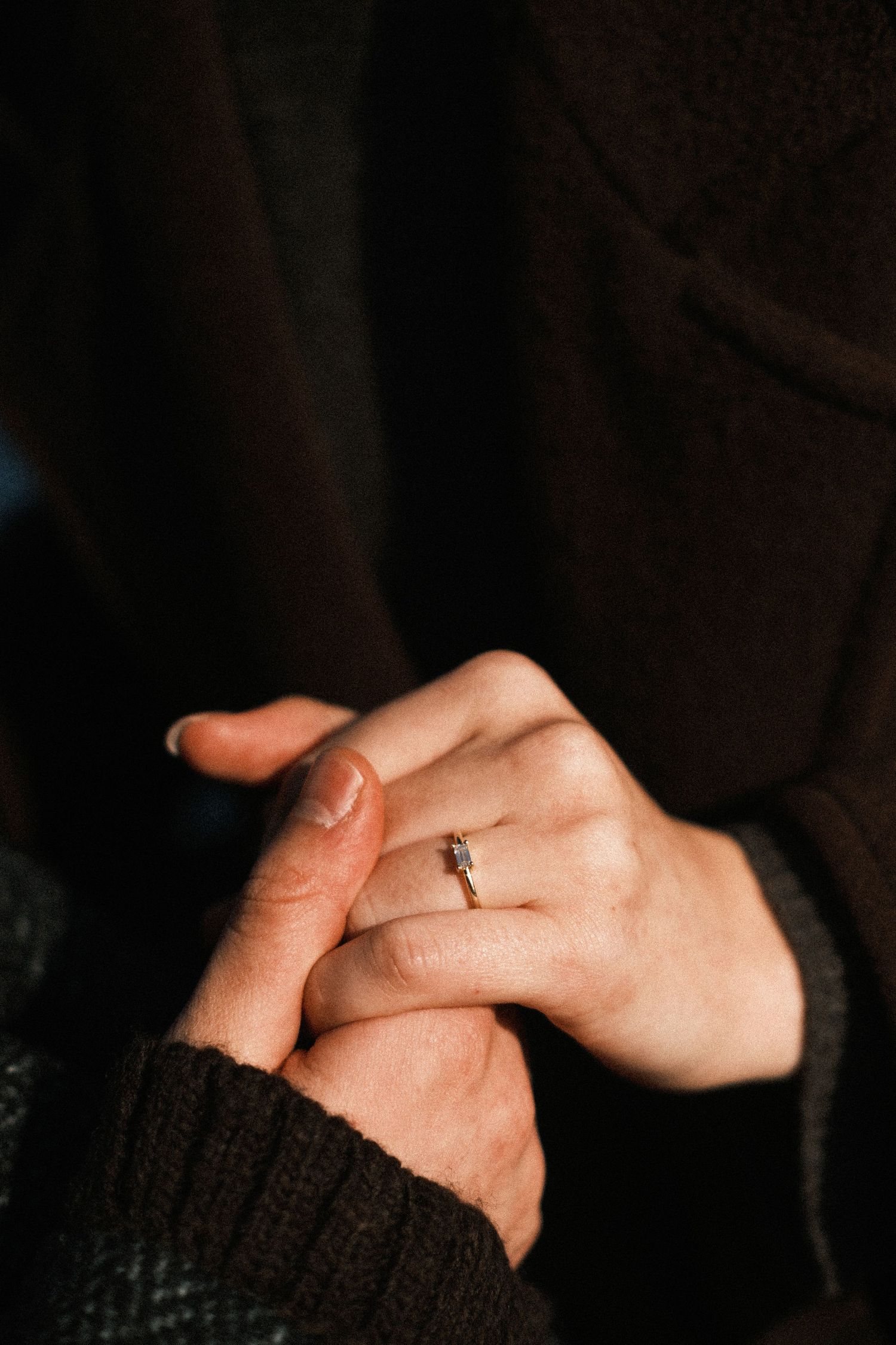 Close-up sequence of hands clasping together in a dark setting showing a romantic moment of intimacy.