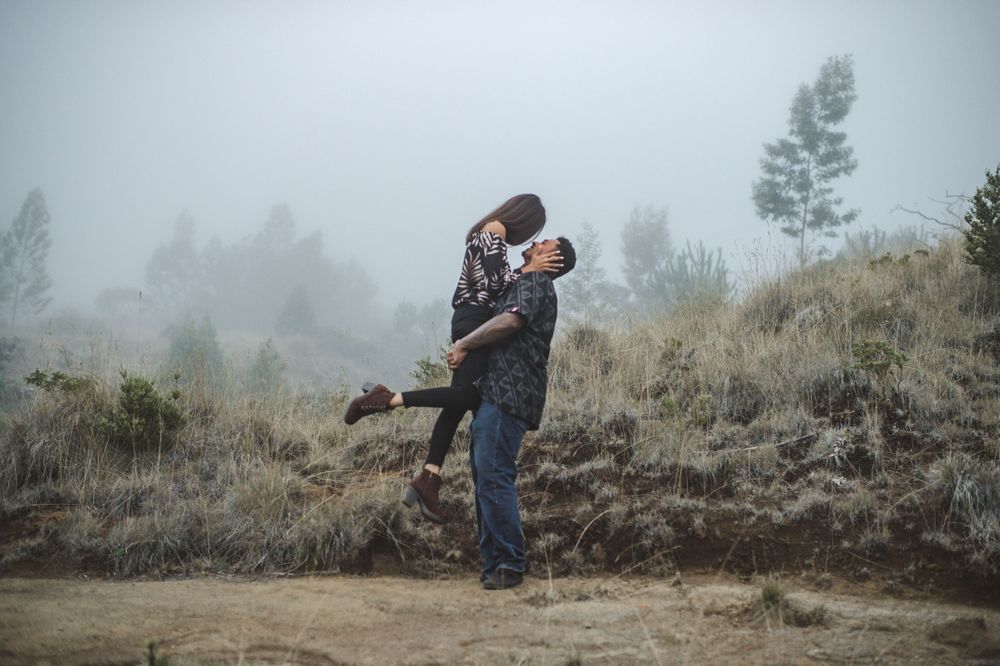 Silhouettes of a couple embracing on a misty hillside.