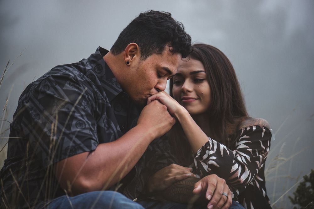 Couple embraces in soft, misty lighting against natural backdrop.